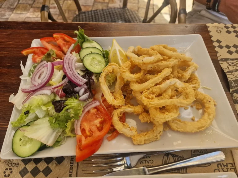 Calamares fritos acompañados de ensalada variada y rodajas de limón.
